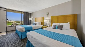 A hotel room with two beds, a large window with a view, and a door leading to a balcony. - Beachside Motel (Fernandina Beach)