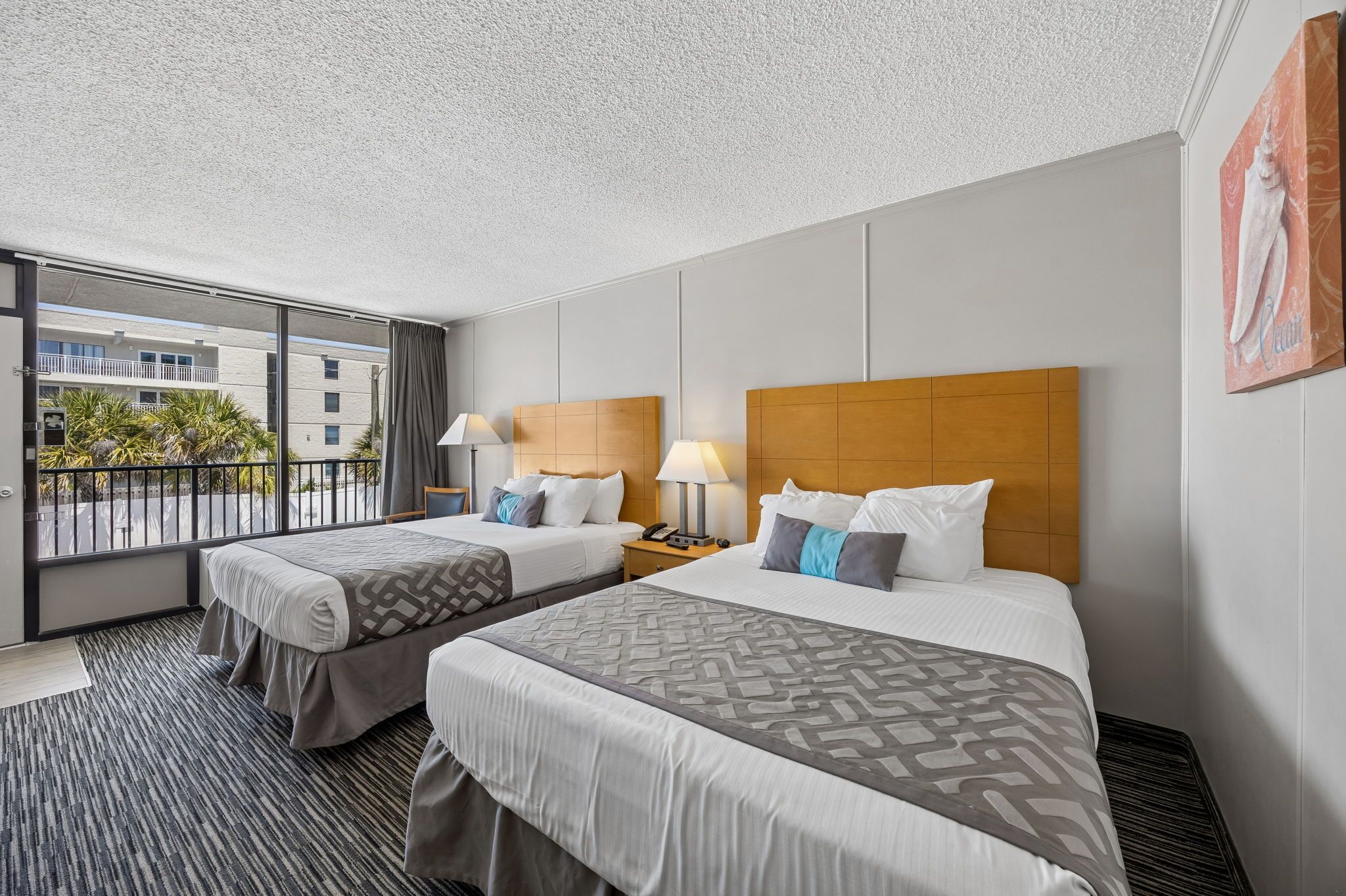 Quarto de hotel com duas camas, varanda e vista para edifícios.