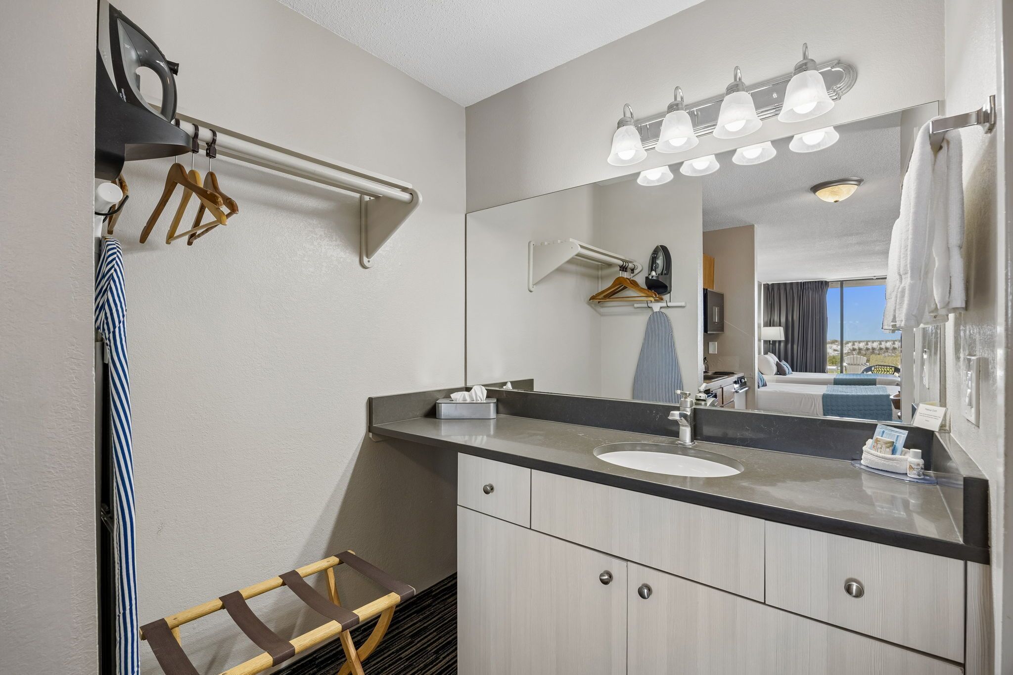 Une salle de bain moderne équipée d’un lavabo, d’un miroir, d’un porte-serviettes et d’un portant à vêtements.