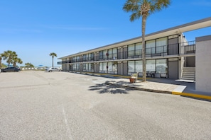A modern hotel with a two-story structure, outdoor seating, and palm trees. - Beachside Motel (Fernandina Beach)