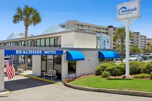 A beachfront motel with a blue awning, an American flag, and a signboard. - Beachside Motel (Fernandina Beach)