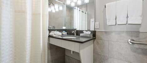 A modern bathroom with a shower curtain, a sink, a mirror, and a towel rack.
