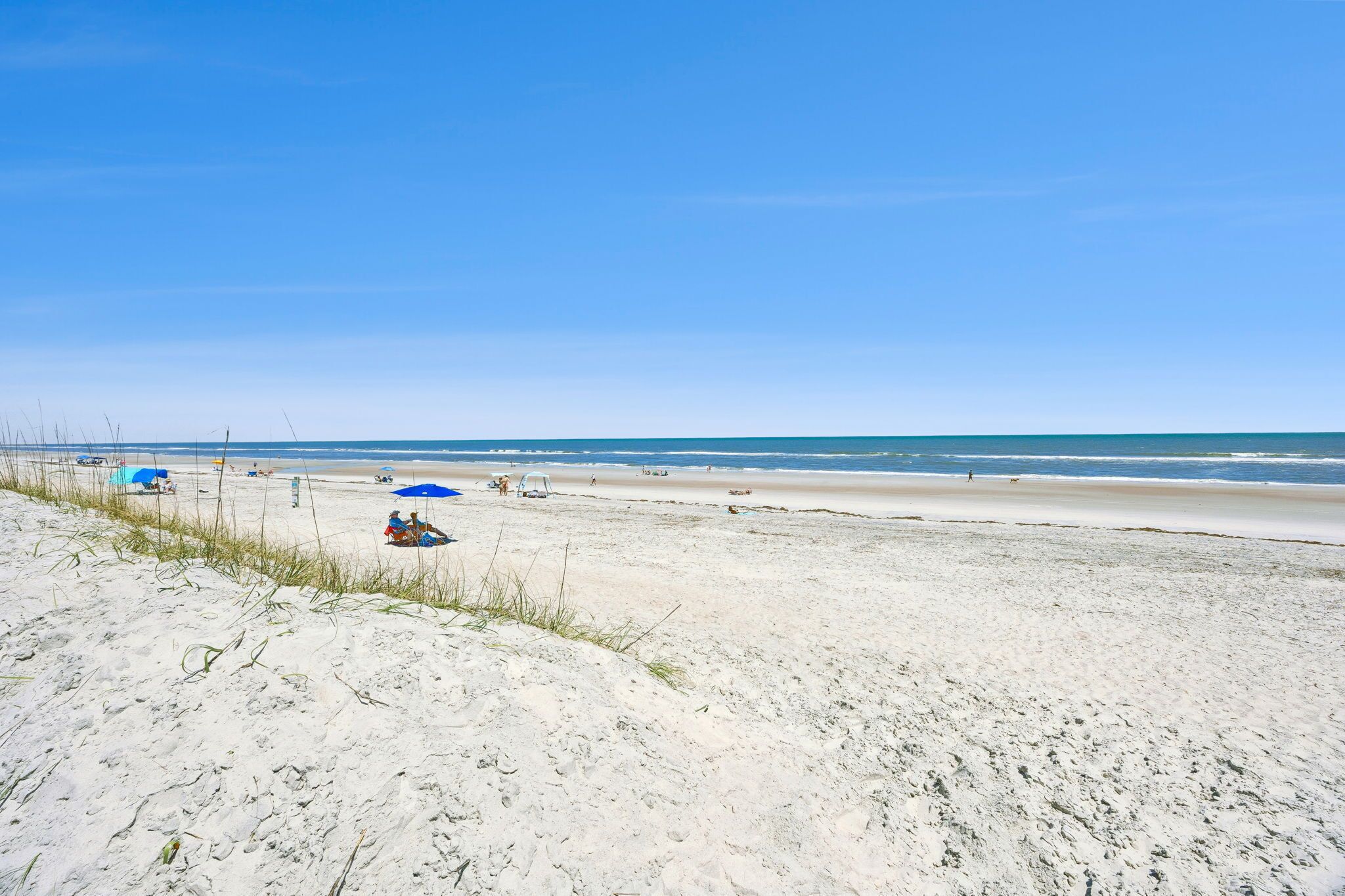 Une plage de sable, quelques parasols et un ciel dégagé.