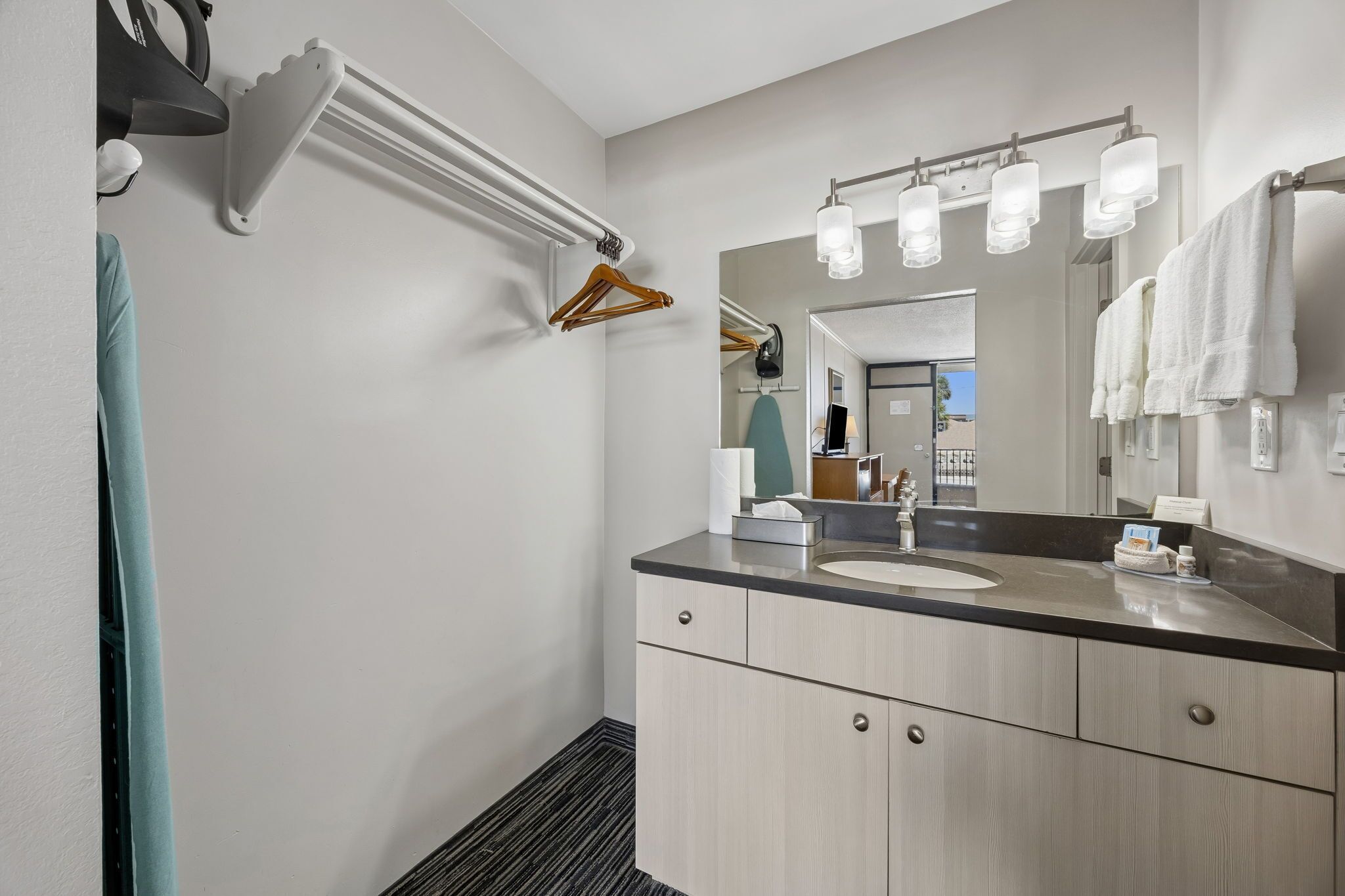 Une salle de bain moderne équipée d’un lavabo, d’un miroir, d’un porte-serviettes et d’une serviette suspendue.