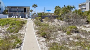 A beachfront property with a boardwalk, beach chairs, and a building with balconies. - Beachside Motel (Fernandina Beach)