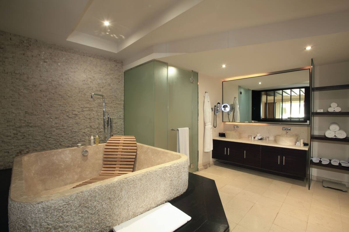 A modern bathroom with a freestanding bathtub, a large mirror, and a vanity with a sink and storage cabinets.