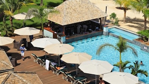 Un complexe hôtelier doté d’une piscine, de chaises longues, de parasols et d’une plage bordée de palmiers.