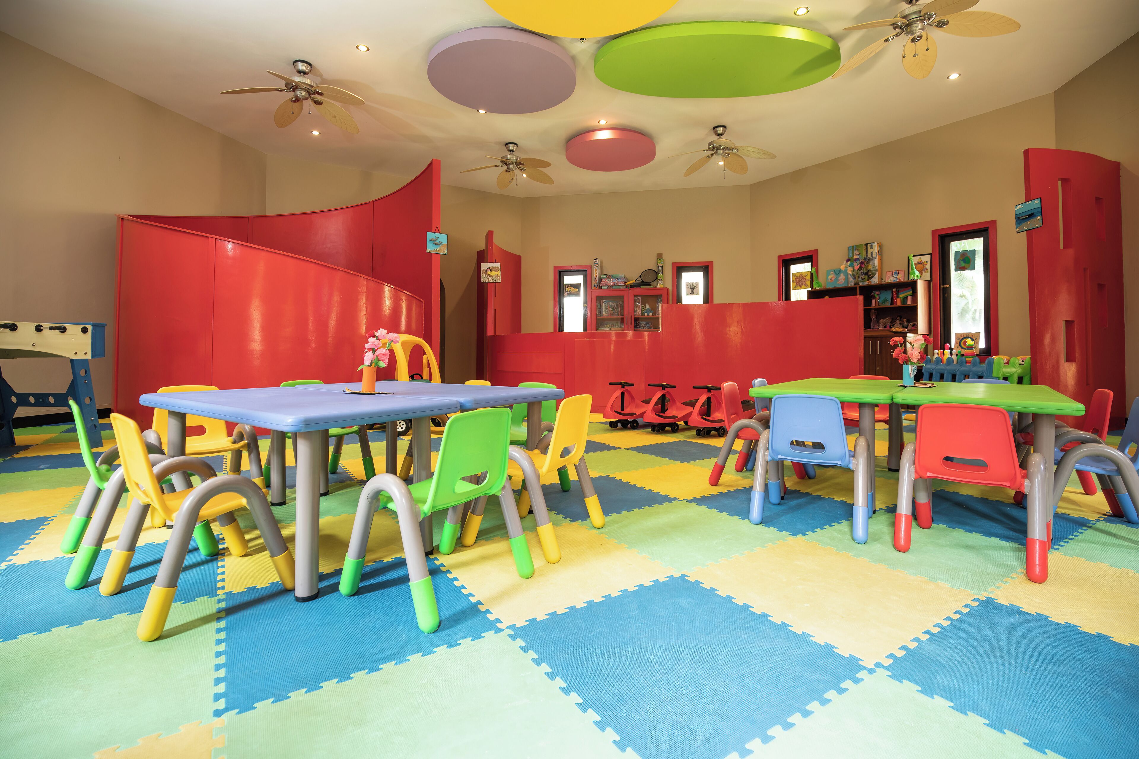 A brightly colored children's playroom with tables, chairs, and toys.