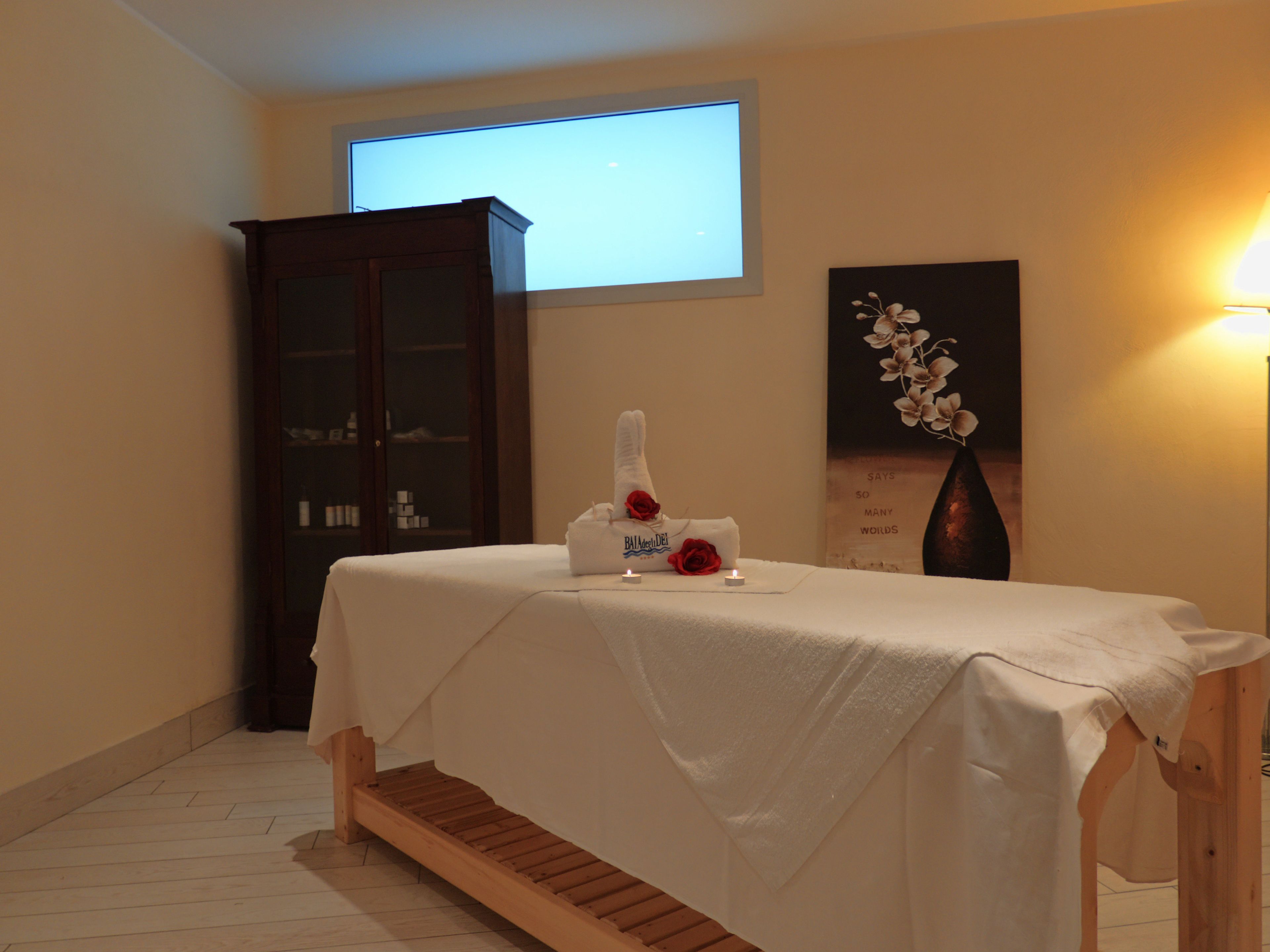 A room with a bed, a wooden cabinet, a projector screen, and a wall-mounted artwork.