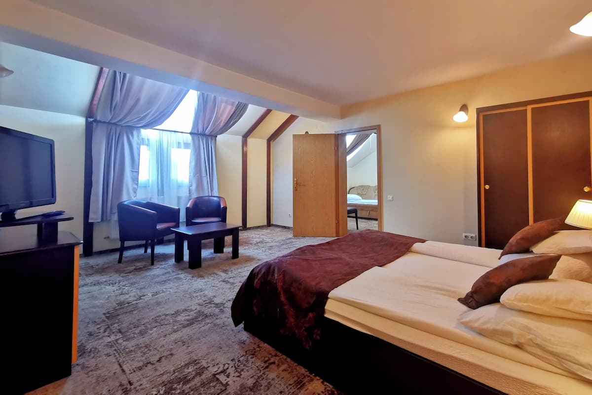 Une chambre d’hôtel avec un lit, un bureau équipé d’un ordinateur, une chaise, un téléviseur et une fenêtre avec des rideaux.