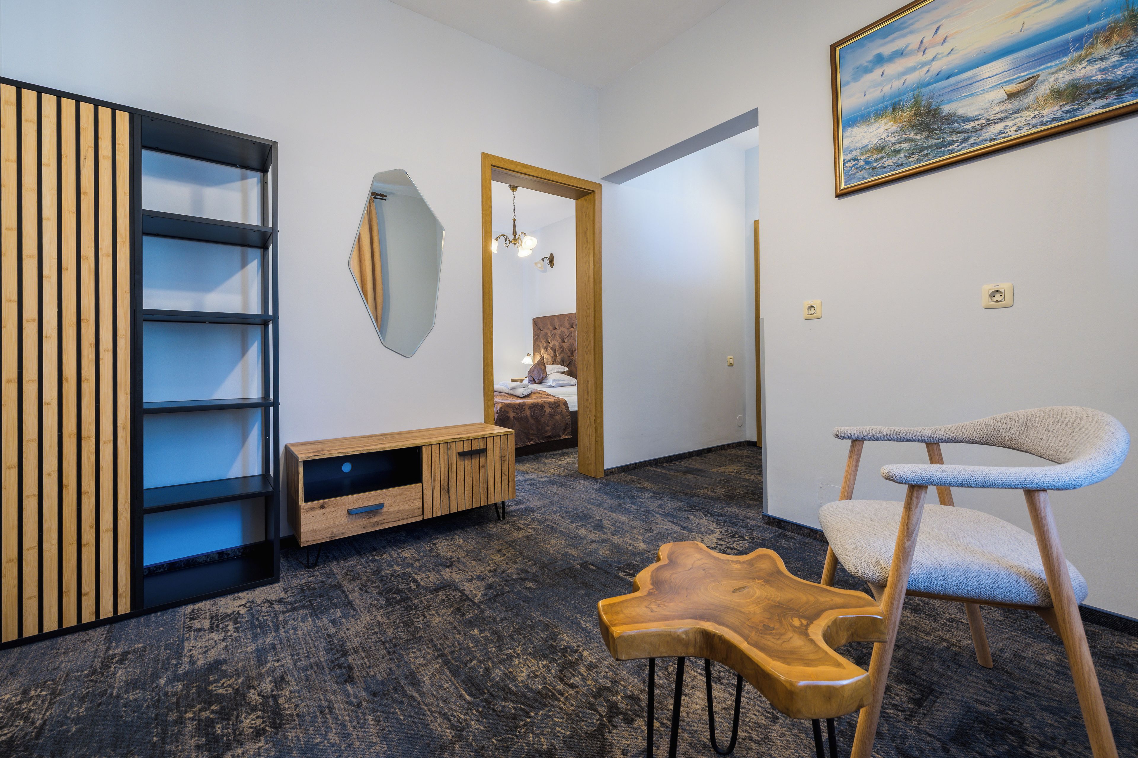 Een modern interieur met een houten kast, een bijzondere houten stoel, een schilderij aan de muur en een spiegel.