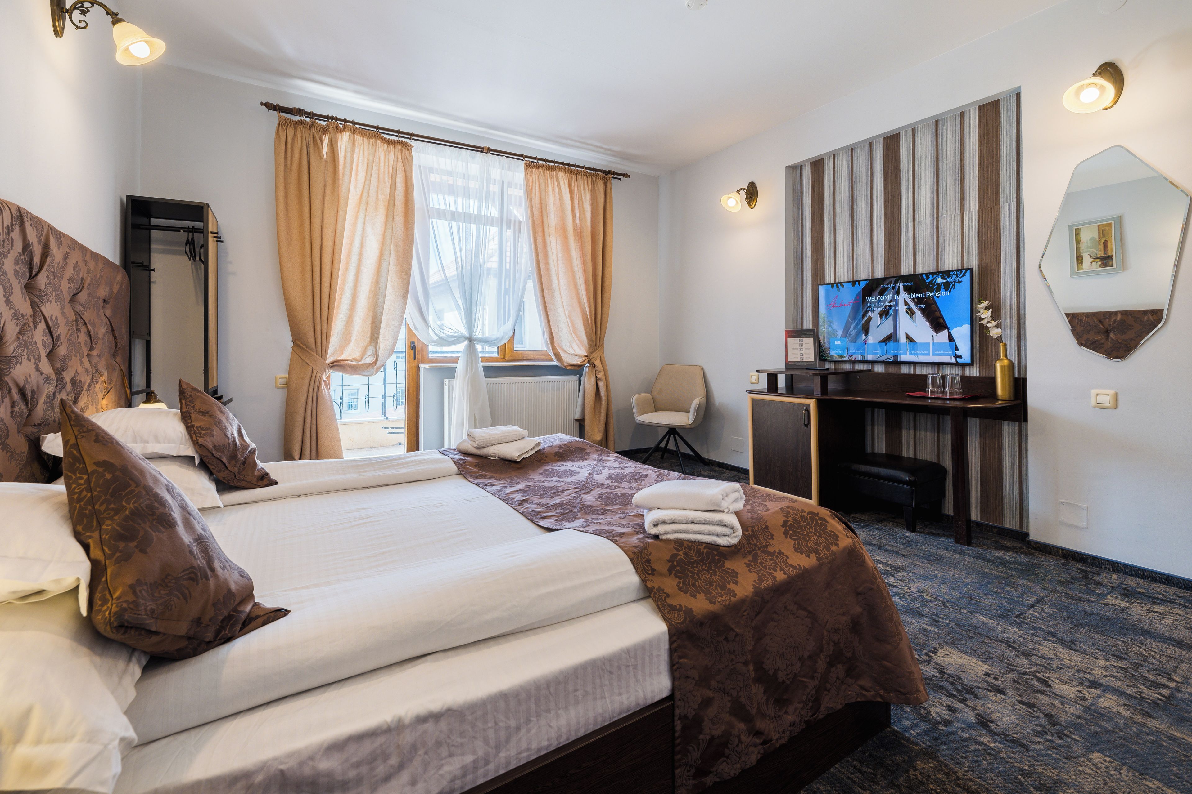Une chambre d’hôtel avec un grand lit, un bureau avec une télévision, une chaise et une fenêtre avec des rideaux.
