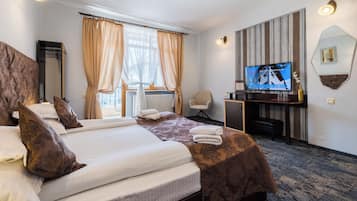 Une chambre d’hôtel avec un grand lit, un bureau avec une télévision, une chaise et une fenêtre avec des rideaux.