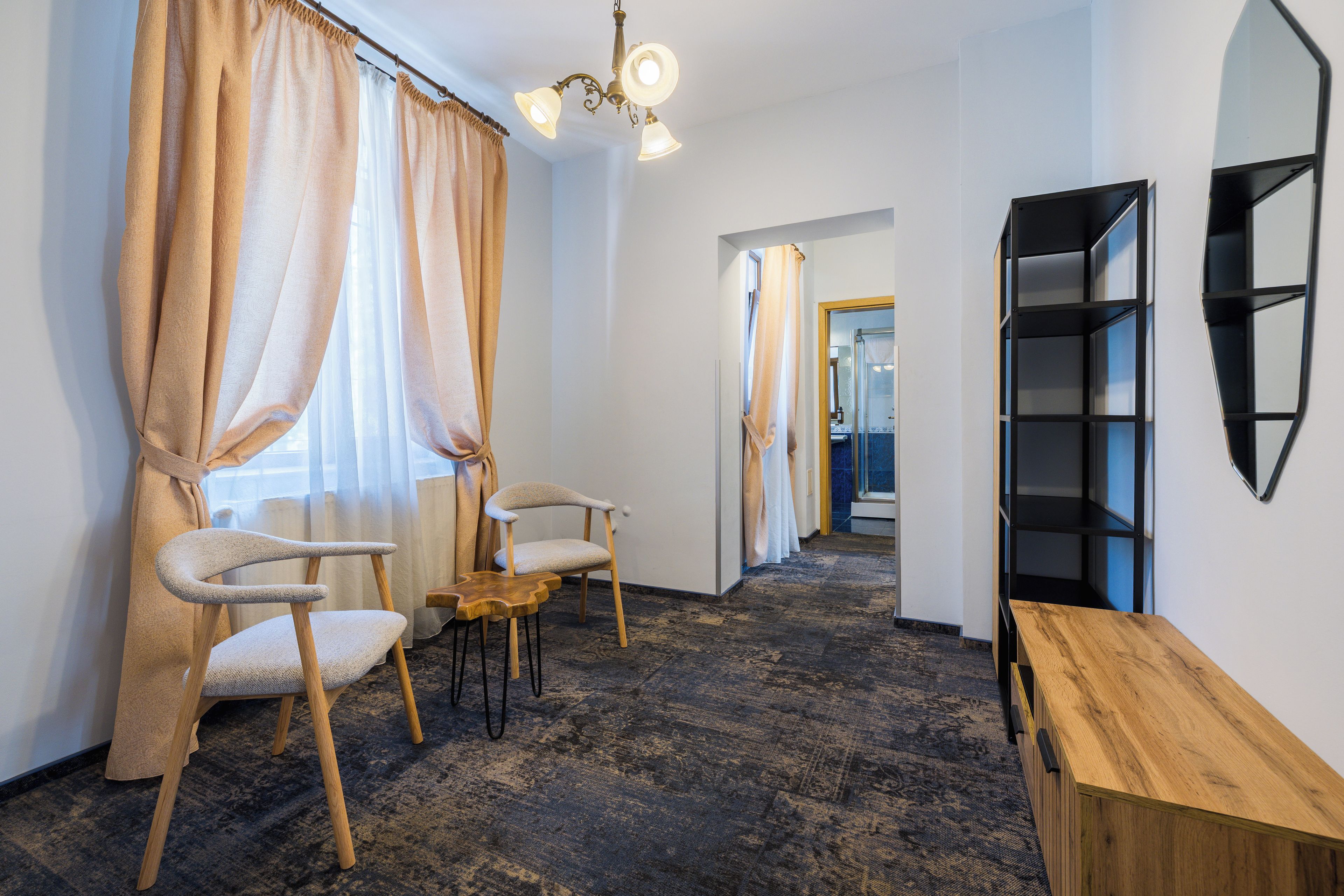 A hallway with a wooden bench, two chairs, a mirror, and a ceiling light fixture.