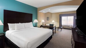A hotel room with a large bed, two bedside tables with lamps, a desk with a chair, a television, and a large window with curtains. - La Quinta Inn & Suites by Wyndham Sebring (Sebring)