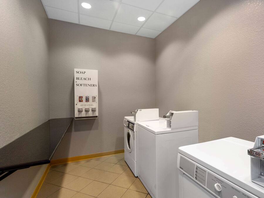 A laundry room with a washing machine, dryer, and a soap and bleach softener dispenser.