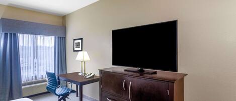 A hotel room with a bed, desk, chair, television, and a cabinet.