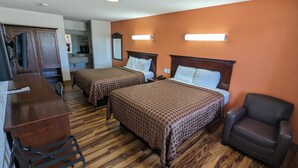 A hotel room with two beds, a desk, a chair, and a bathroom visible in the background. - Hillcrest Inn & Suites (Ozona)