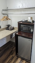 Una kitchenette compacta con un refrigerador de acero inoxidable, un microondas y una encimera de madera.