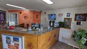 A reception desk with a 'Welcome' sign, a clock, and a framed welcome sign. - Hillcrest Inn & Suites (Ozona)