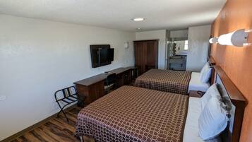 A hotel room with two beds, a desk, a chair, a television, and a bathroom visible through an open door.