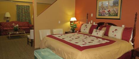 A bedroom with a bed, a bench, a sofa, a lamp, and a painting on the wall.