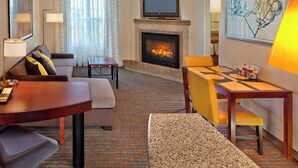 A hotel room with a fireplace, a sofa, a dining table, and a TV mounted above the fireplace. - Residence Inn by Marriott Waldorf (Waldorf)