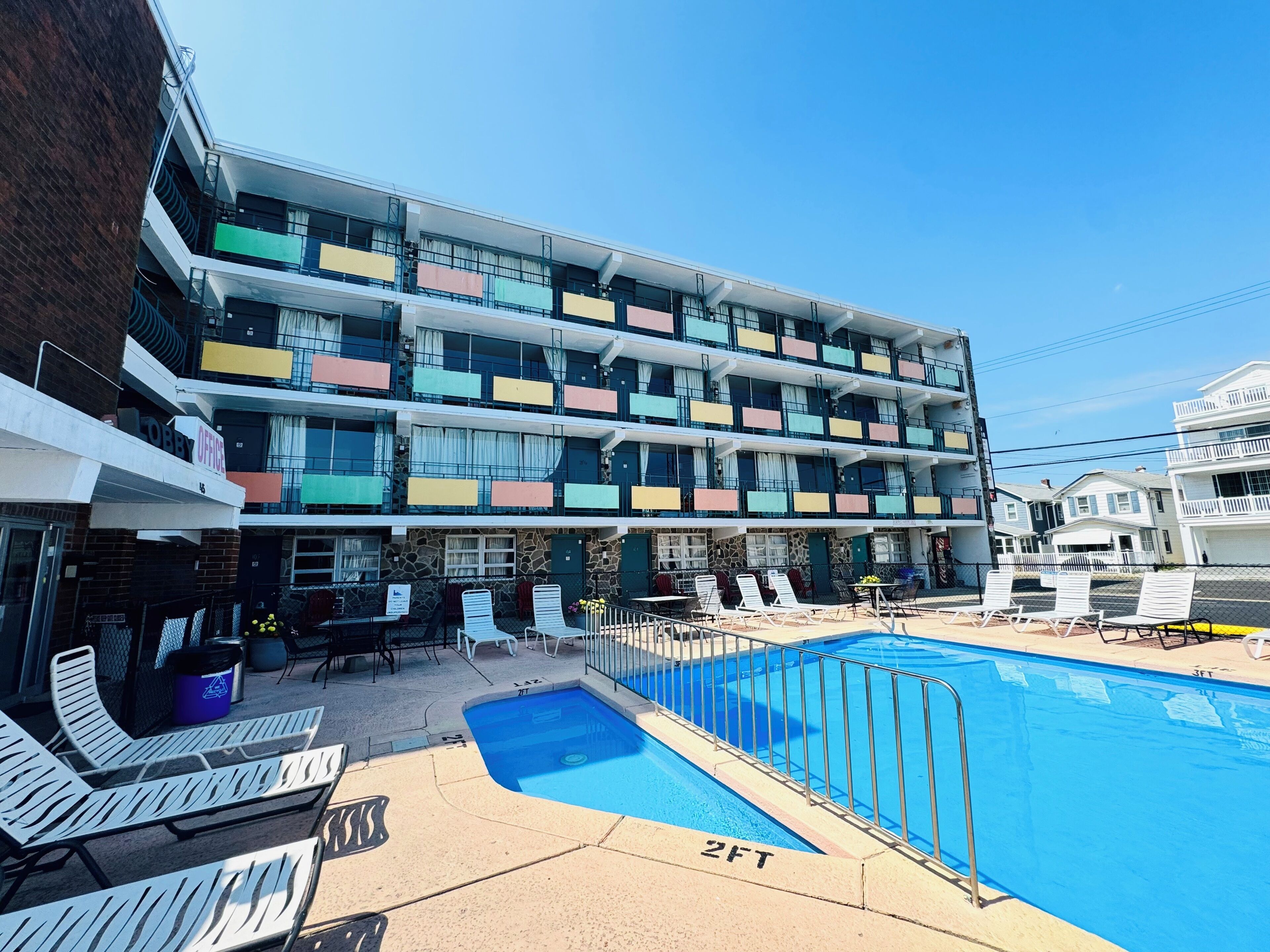 Un hôtel à plusieurs étages doté de balcons, d’une piscine et d’un espace extérieur aménagé pour s’asseoir.