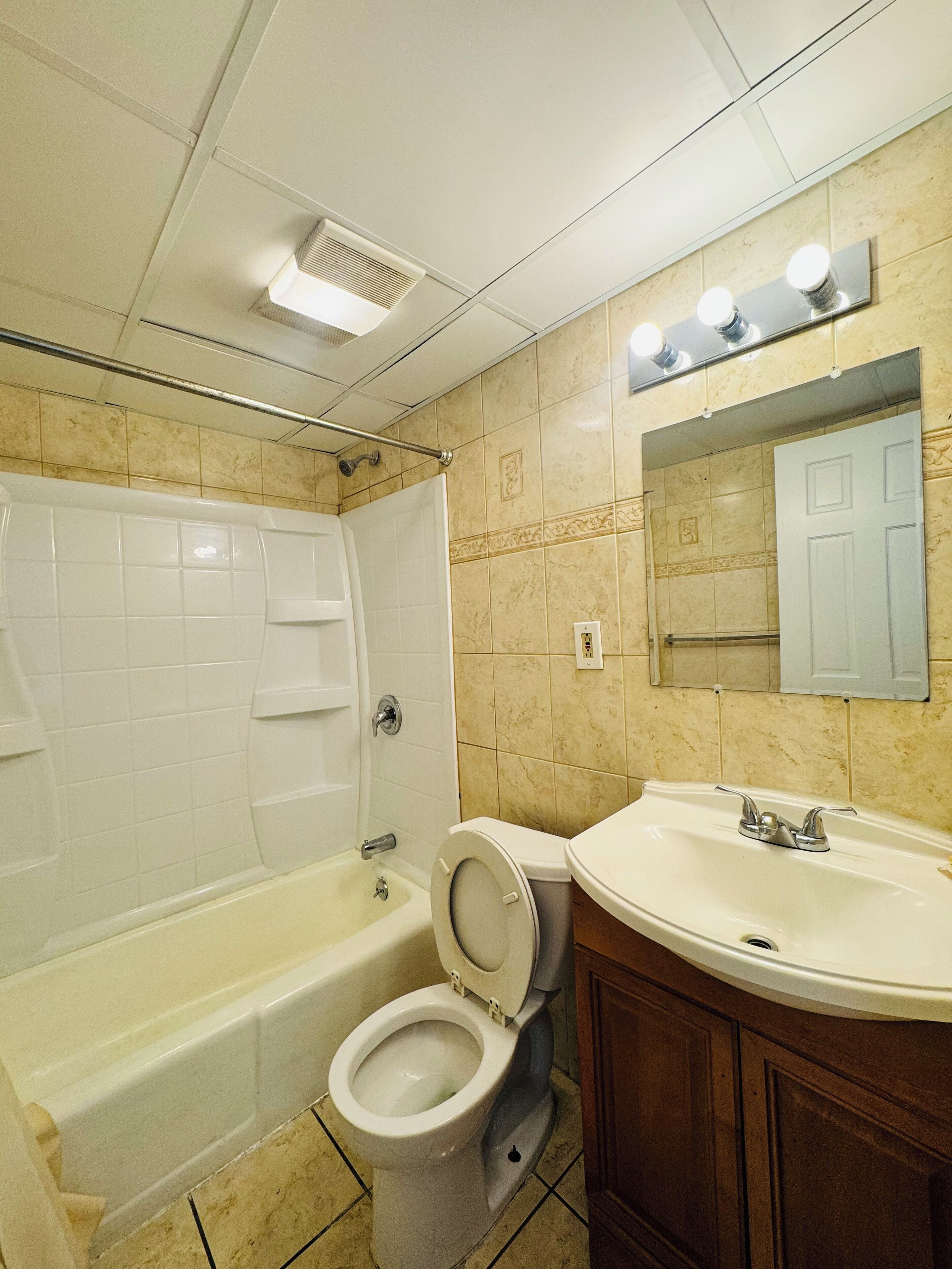 A bathroom with a bathtub, toilet, sink, and mirror.