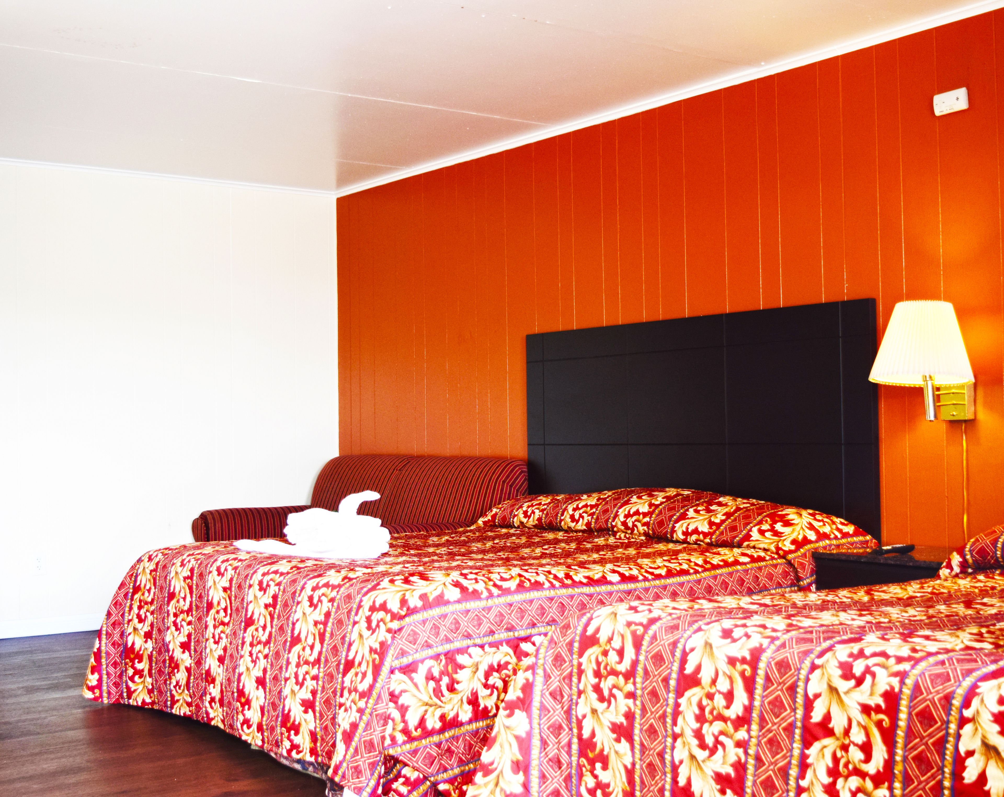 Une chambre d’hôtel avec un grand lit, une table de chevet, une lampe et un interrupteur fixé au mur.