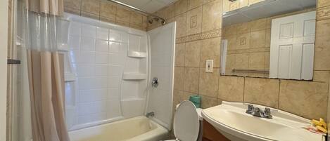 A bathroom with a bathtub, toilet, and sink.