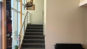 Una escalera con una estatua de leopardo en la parte superior, una silla negra y un muro de cristal con una planta.