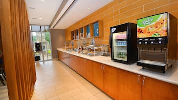 A breakfast bar with a juice dispenser and a refrigerator.