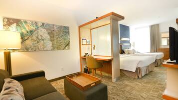 A hotel room with a sofa, a wooden tray, a desk, a chair, a bed, and a large mirror.