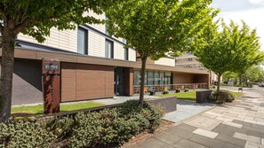 A modern building with a Staybridge Suites sign, outdoor seating, and a well-maintained garden area. - Staybridge Suites Newcastle by IHG (Newcastle-upon-Tyne)