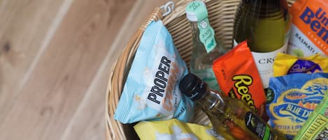 A wicker basket filled with various food items including snacks and a bottle of oil.