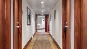 A hallway with wooden doors, a fire extinguisher, and a sign indicating an exit. - Staybridge Suites Newcastle by IHG (Newcastle-upon-Tyne)