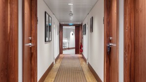 A hallway with wooden doors, a fire extinguisher, and a sign indicating an exit. - Staybridge Suites Newcastle by IHG (Newcastle-upon-Tyne)