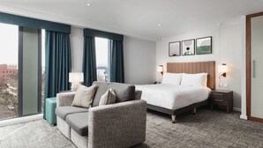 A hotel room with a large bed, a sofa, a small table, and a view of the city. - Staybridge Suites Newcastle by IHG (Newcastle-upon-Tyne)