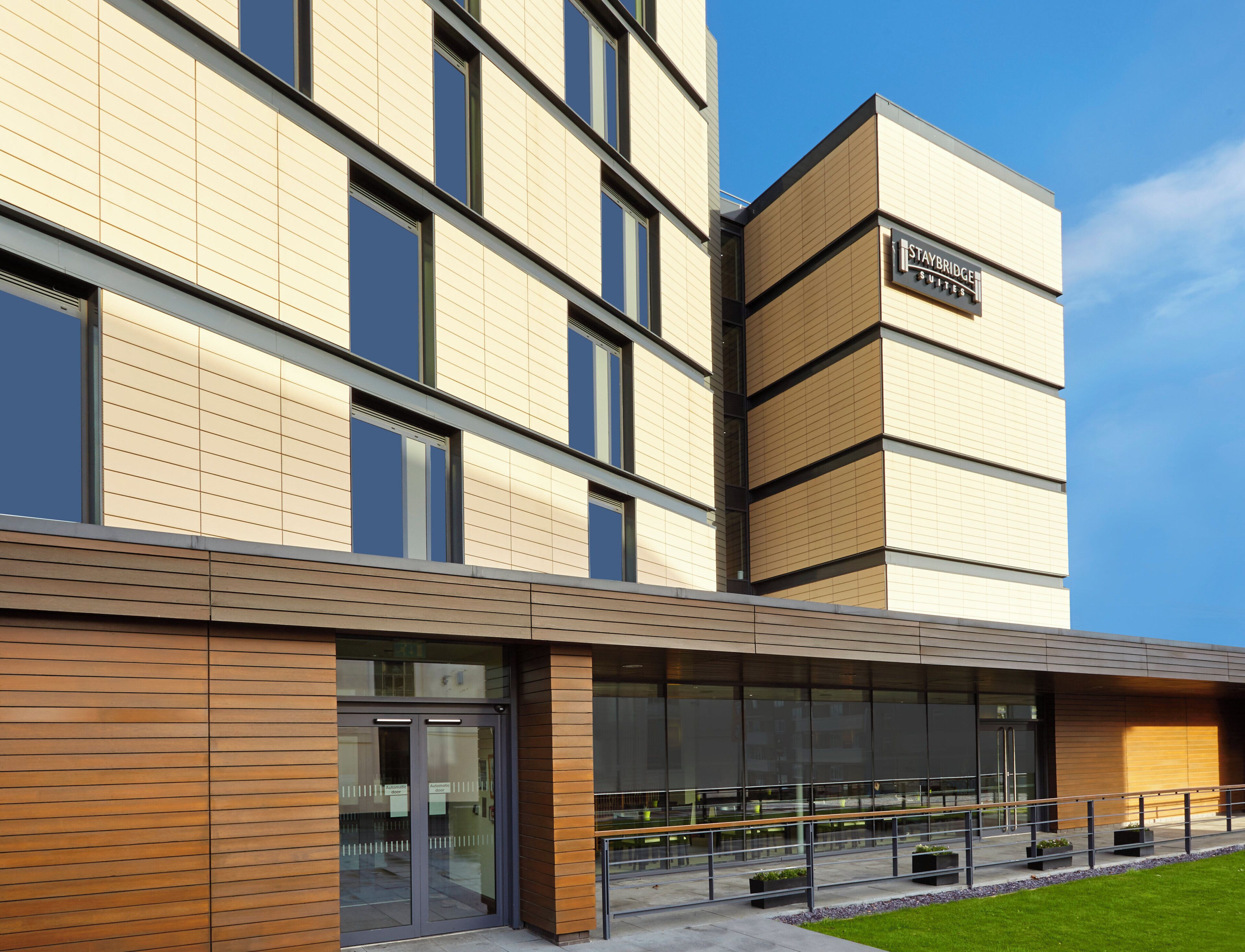 A multi-story hotel with a modern facade, large windows, and a sign indicating 'Staybridge Suites.'