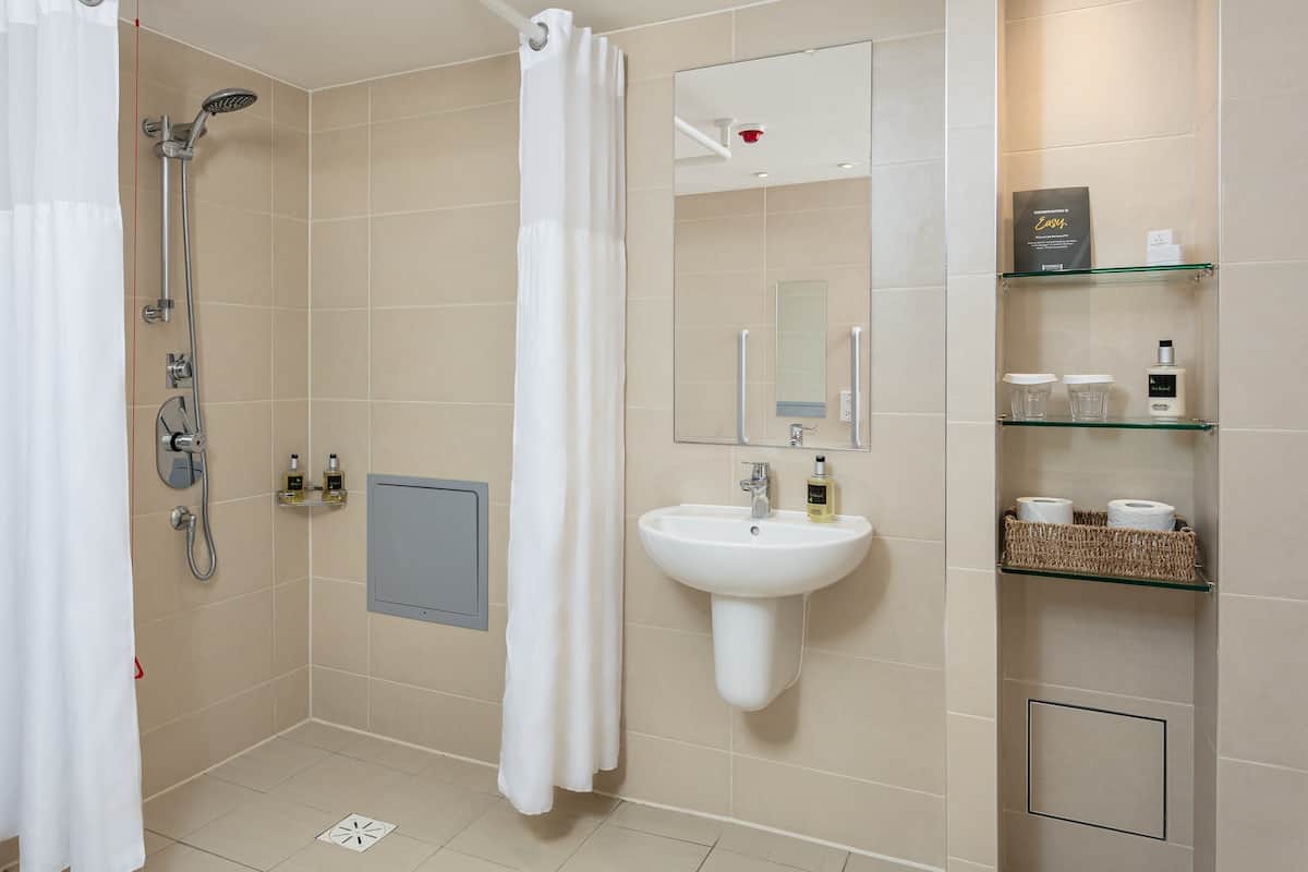 Ein modernes Badezimmer mit Dusche, Waschbecken und Regalen mit Pflegeprodukten.