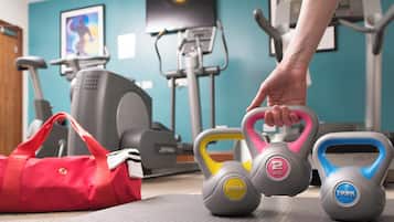 Un gimnasio con equipo de ejercicio, una bolsa roja y una pared con un cuadro.