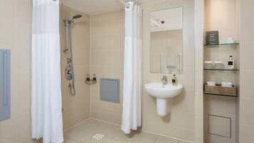 A modern bathroom with a shower, sink, and storage shelves.