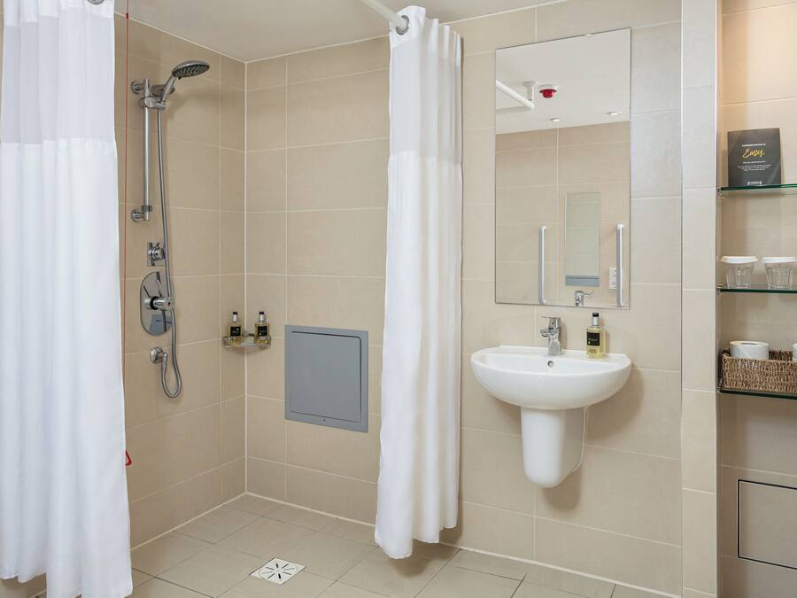 A modern bathroom with a shower, sink, and storage shelves.
