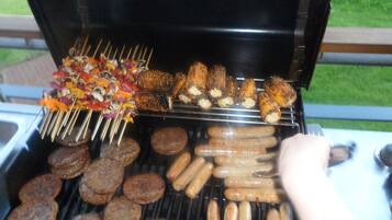 A grill with various meats and vegetables being cooked.