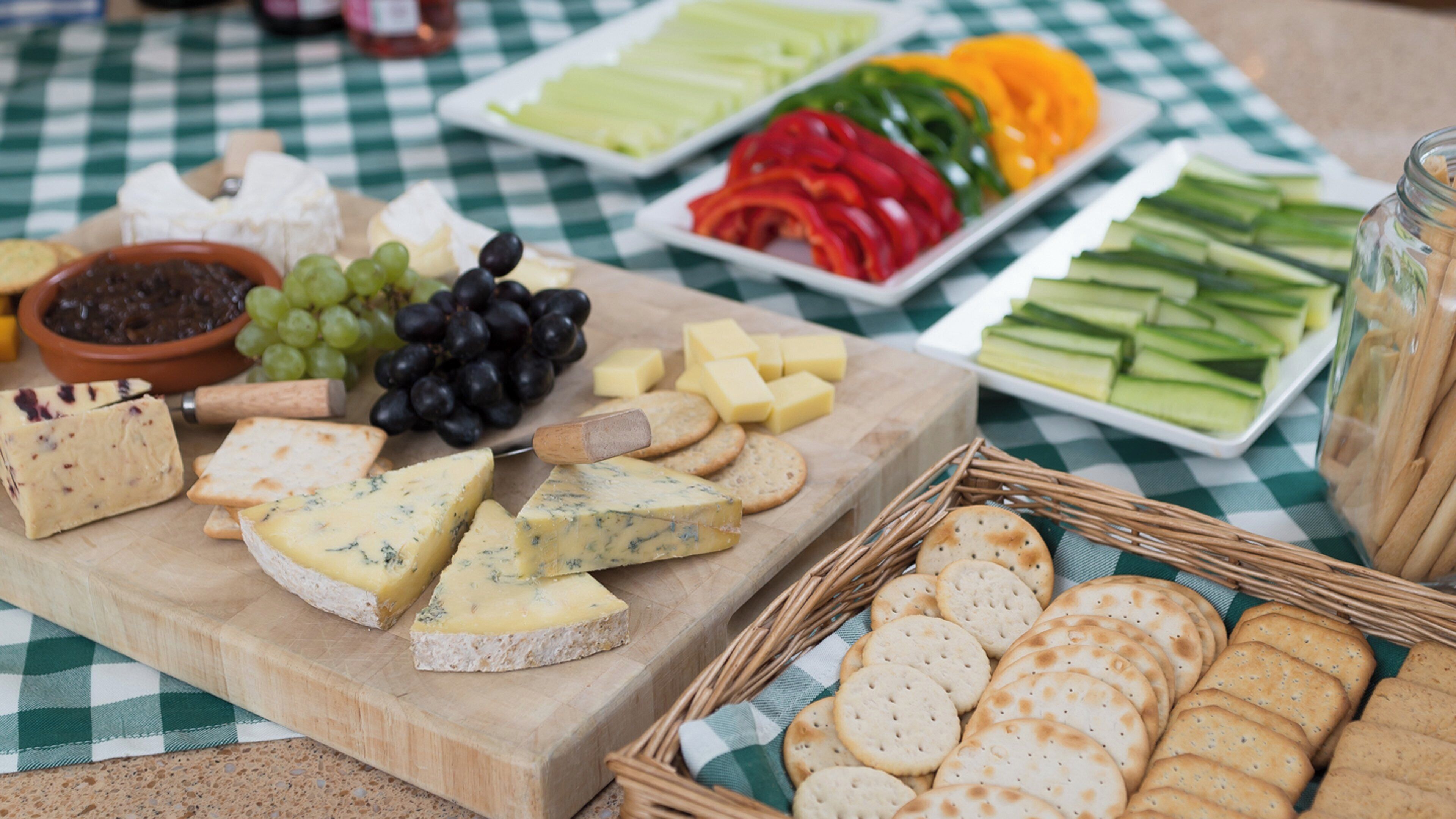 A cheese board with various cheeses, crackers, and grapes.