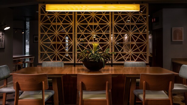 A conference room with a long wooden table, six chairs, and a potted plant in the center. - Staybridge Suites Newcastle by IHG (Newcastle-upon-Tyne)
