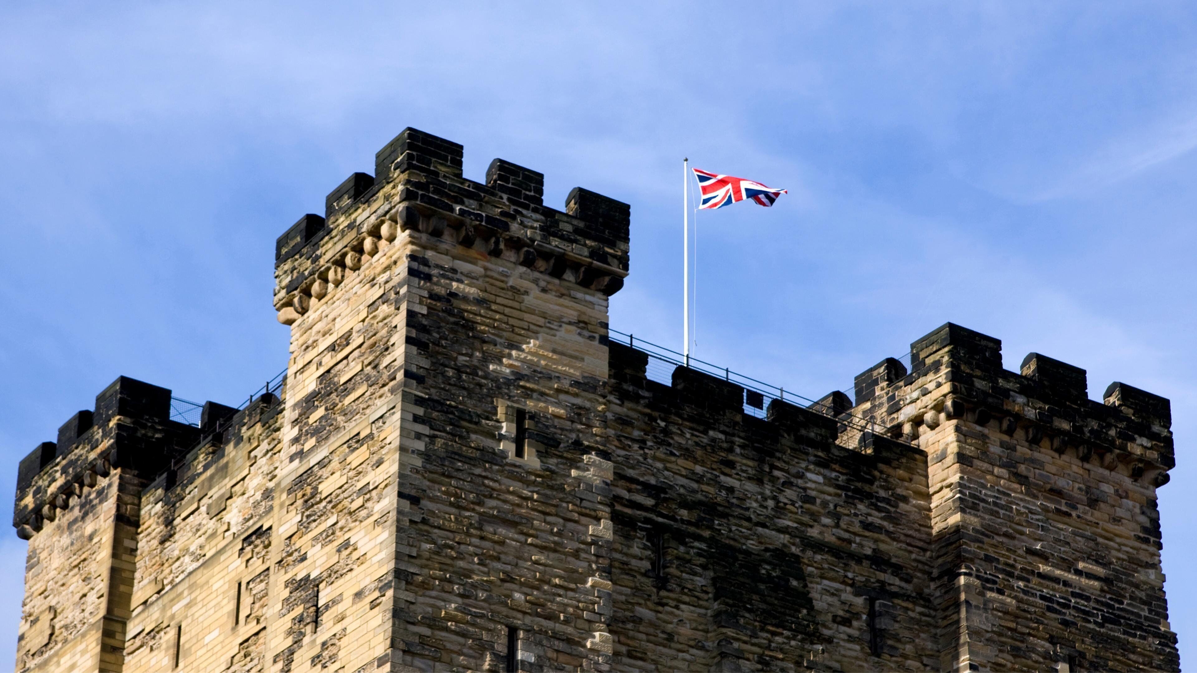 Un château de pierre historique, doté de créneaux et arborant un drapeau.