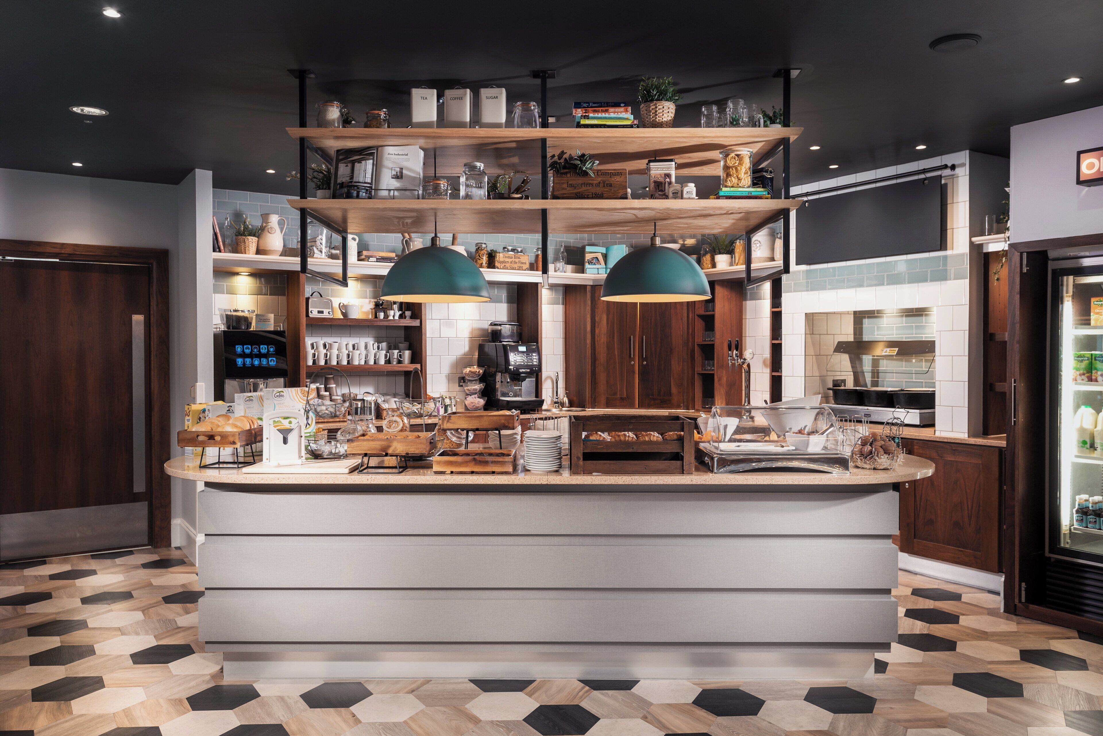 Una cocina moderna con una isla central, estanterías de madera y una zona para preparar café.