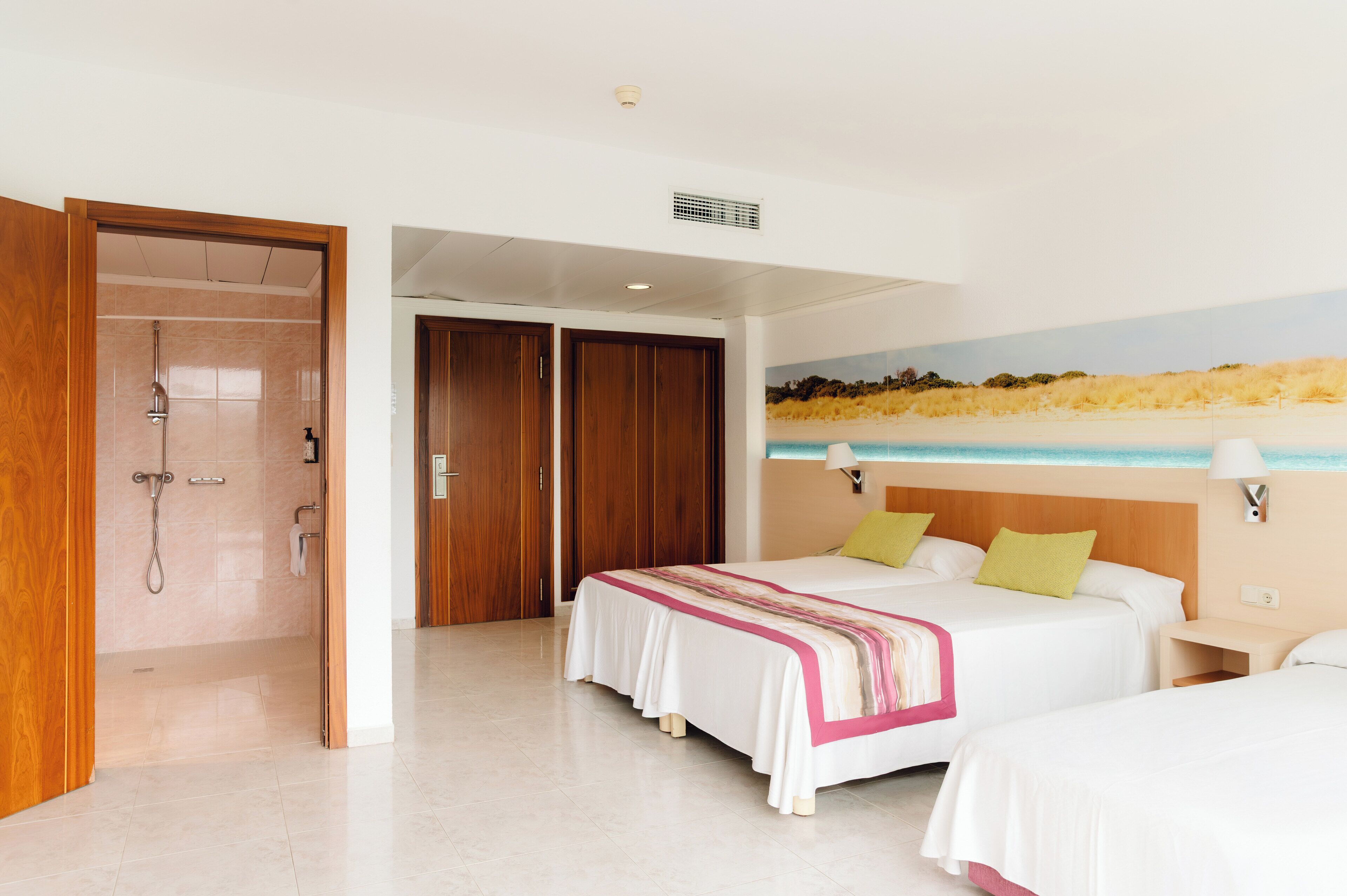 Ein Hotelzimmer mit zwei Betten, einer Duschkabine und einem Wandgemälde zum Strandthema.